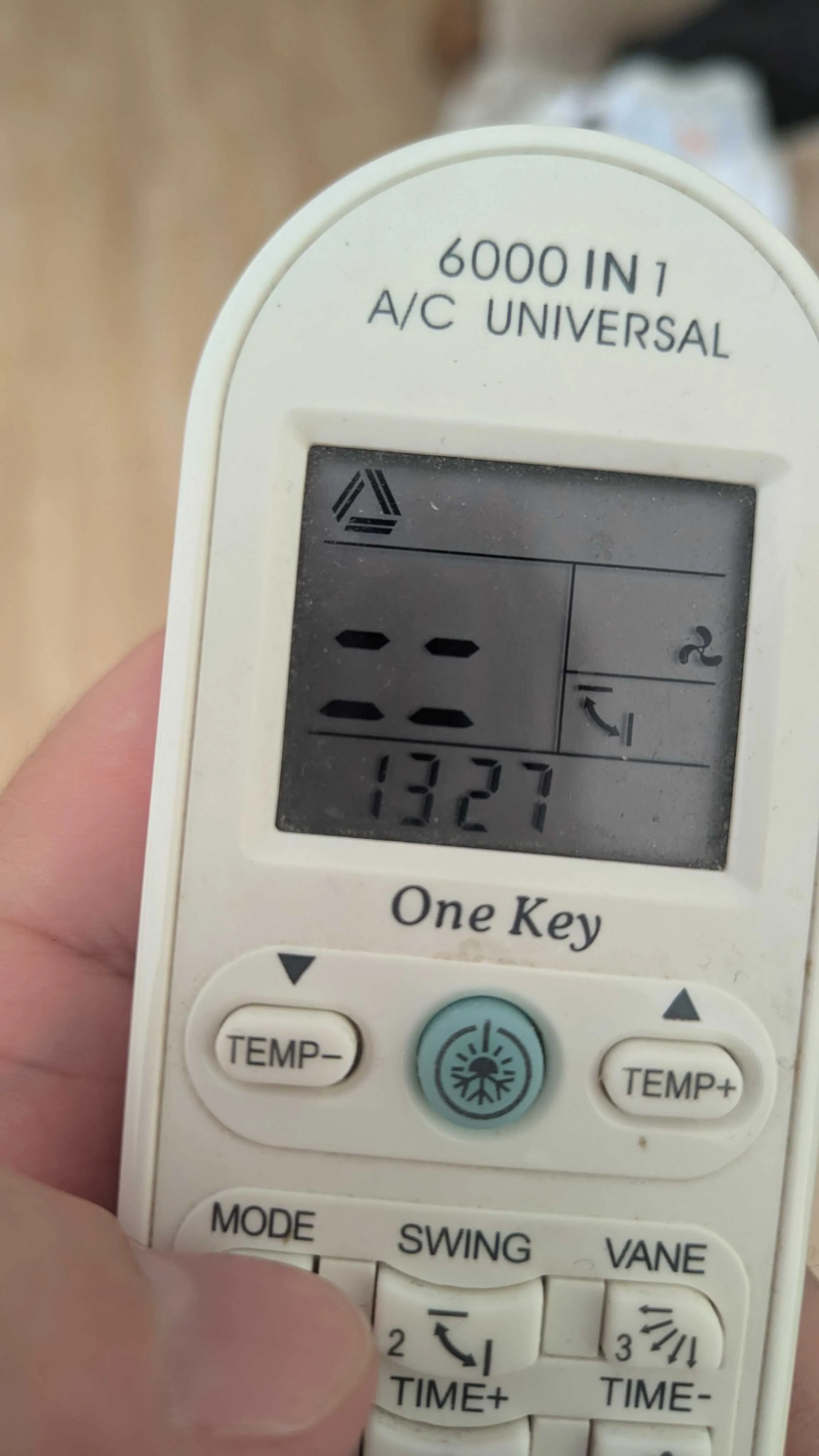 Me holding an universal A/C remote. It is displaying that the current mode is triangle with two strips.